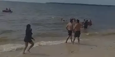 Momento em que o jovem é resgatado por bombeiros na praia