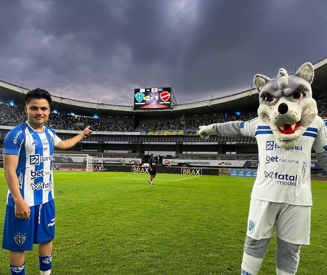 Esli Garcia e Lobo Mau apontam para o placar do jogo.