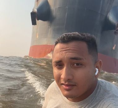 Imagem - Homem navega tranquilamente de rabeta em frente a imenso navio; assista