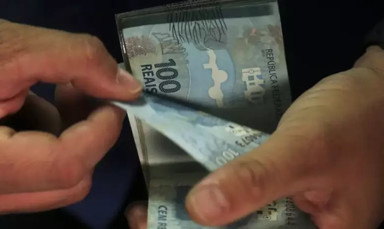 Cédulas de cem reais sendo contadas.