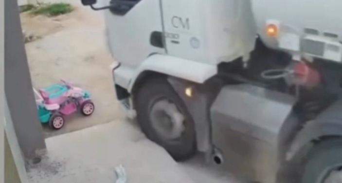 No vídeo, a mãe percebe um caminhão desgovernado vindo em direção e retira rapidamente o filho, que brincava ao lado, da rota de colisão do veículo.