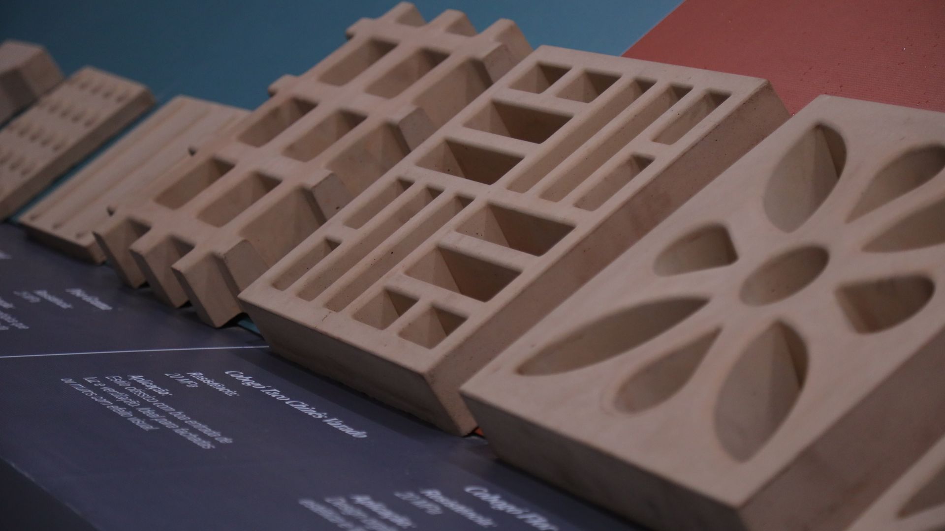 Peças produzidas com rejeito de bauxita, uma inovação desenvolvida em parceria com a USP. O material substitui 35% do cimento na composição, gerando uma redução direta nas emissões de CO₂. 