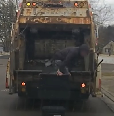 (Momento do flagrante, quando o funcionário de limpeza pública encontra o homem no caminhão de lixo.)