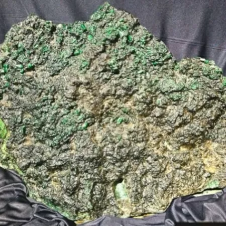 (A peça é descrita como um conglomerado de berilo e xisto, com cristais hexagonais de esmeralda bem preservados, o que aumenta seu valor geológico e comercial.)