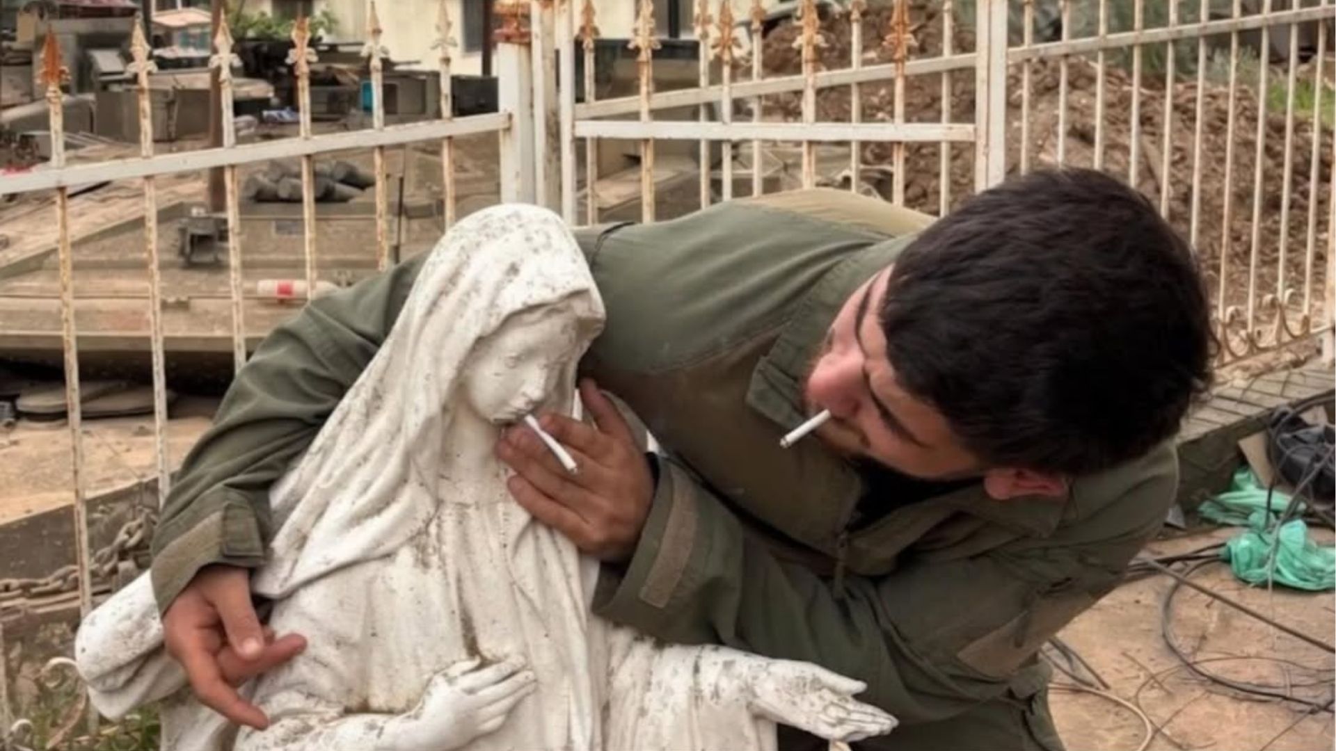 Militar israelense colocando um cigarro na boca de uma estátua da Virgem Maria.