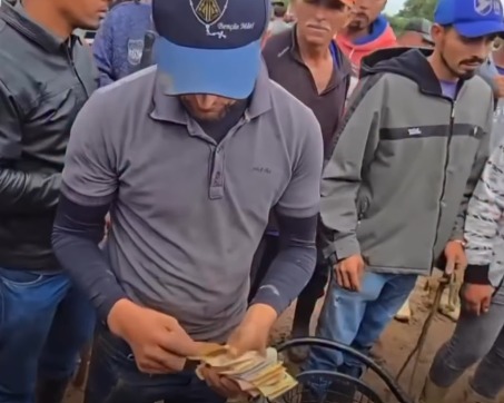 (A gravação registra o momento em que comerciantes e frequentadores da feira se mobilizaram rapidamente para ajudar um vendedor de picolé que perdeu toda a sua mercadoria após um acidente envolvendo um boi bravo.)