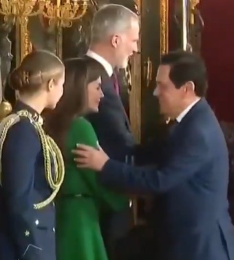 (A rainha Letizia, conhecida por sua elegância e rigor protocolar, manteve a distância com um movimento sutil, evitando o contato.)