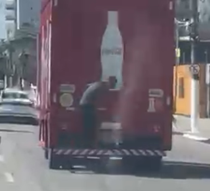 Nas imagens, o homem aparece segurando-se na estrutura externa do veículo em movimento, prática popularmente conhecida como “morcegar”.