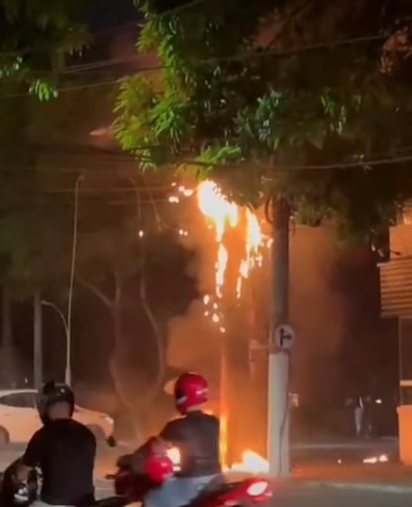 (Vídeos feitos por moradores mostram as chamas atingindo os cabos da rede elétrica, enquanto faíscas eram lançadas sobre a via, causando preocupação entre pedestres e motoristas que passavam pelo local.)