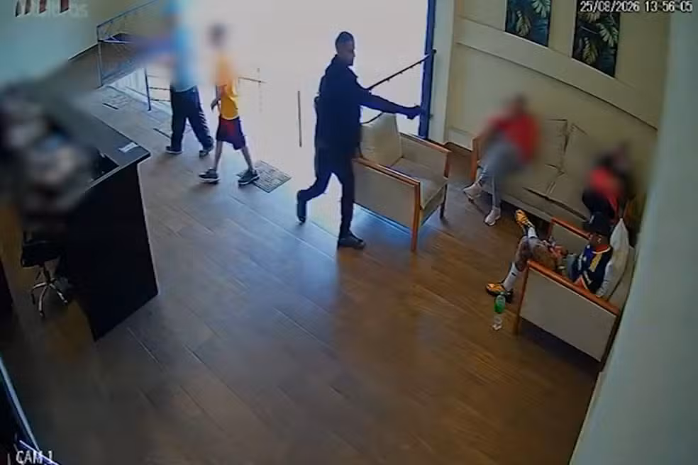 (Na gravação, a vítima aparece sentada em uma poltrona quando é surpreendida por um homem armado.)