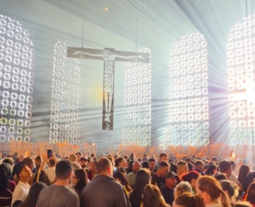 (Nas imagens, a luz solar atravessa a capela e se espalha pelo ambiente, criando um efeito visual que se destaca em meio à movimentação dos visitantes.)
