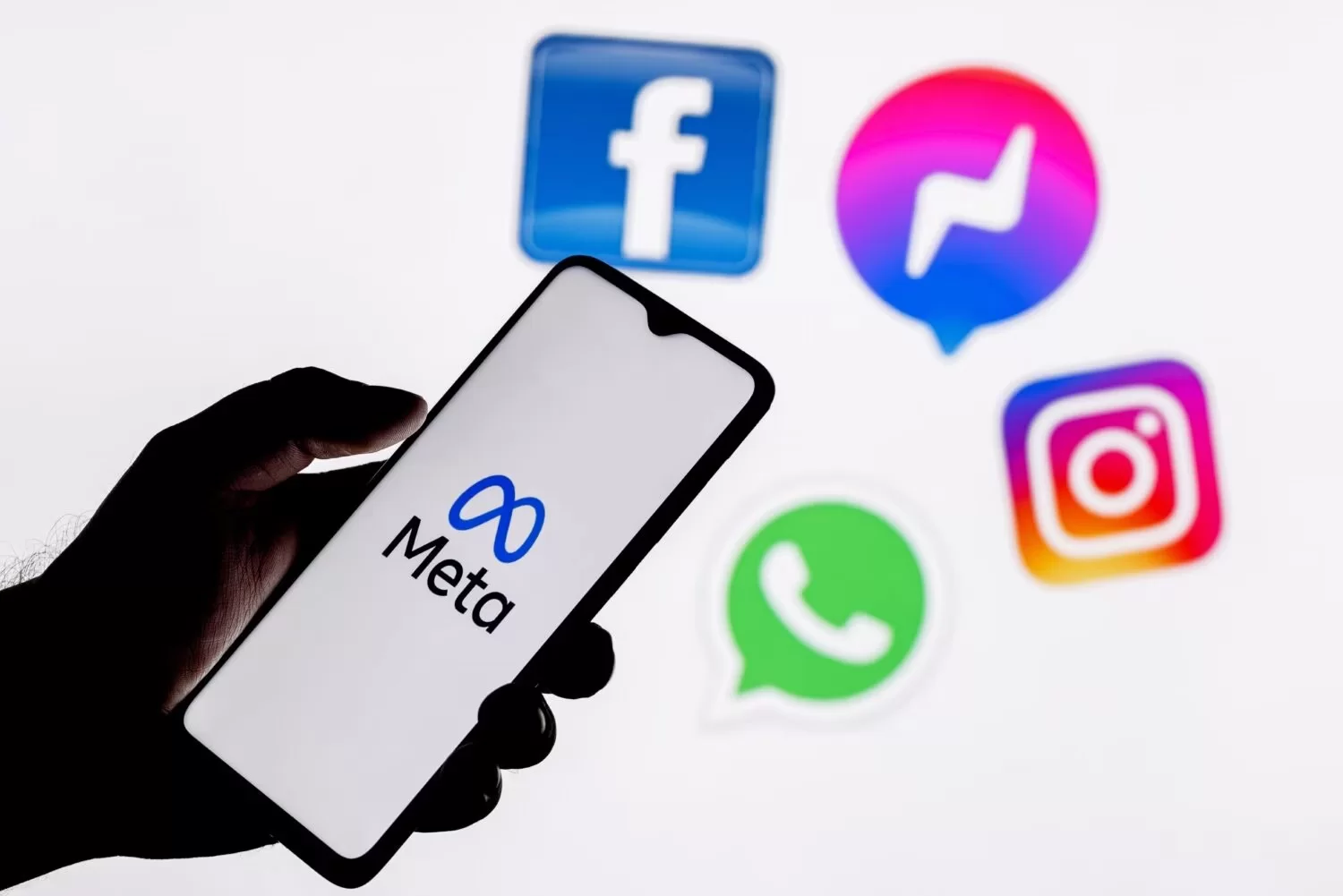 Pessoa segurando celular com o símbolo da Meta na tela.
